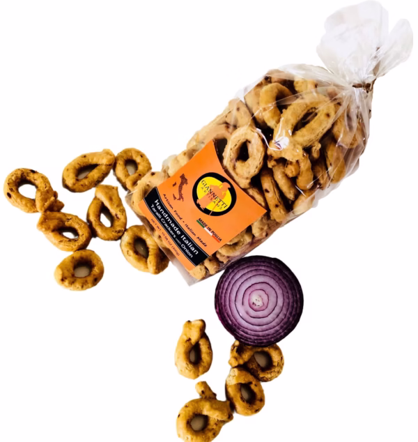 Top view of a transparent bag of Giannetti Artisans onion taralli on a white background with a red onion and loose crackers