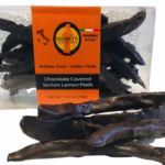 Clear box of Giannetti Artisans chocolate lemon peels with a few lemon peels on the side of the box for demonstrative purposes