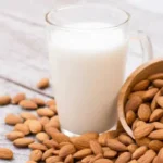 Glass of almond milk with almonds poured next to the glass for Giannetti Artisans Sicilian Almond Milk Recipe