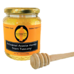 A 17.63 oz jar of Giannetti Artisans Italian Acacia Honey on a white backgorund with wooden honey dipper on the side